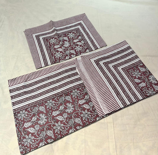 Two fabric placemats with floral and striped patterns on a beige surface